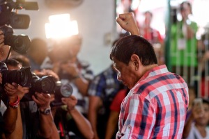 Rodrigo Duterte, Mayor of Davao and presidential candidate, gestures to members of the media at a polling station during the presidential election in Davao, Mindanao, the Philippines on Monday, May 9, 2016. Filipinos began voting in a holly contested presidential election that's seen Rodrigo Duterte, the controversial mayor of Davao City, propelled to the front of the pack with his tough talk to combat crime and deal with traffic-clogged roads in the Philippines. Photographer: Veejay Villafranca/Bloomberg via Getty Images